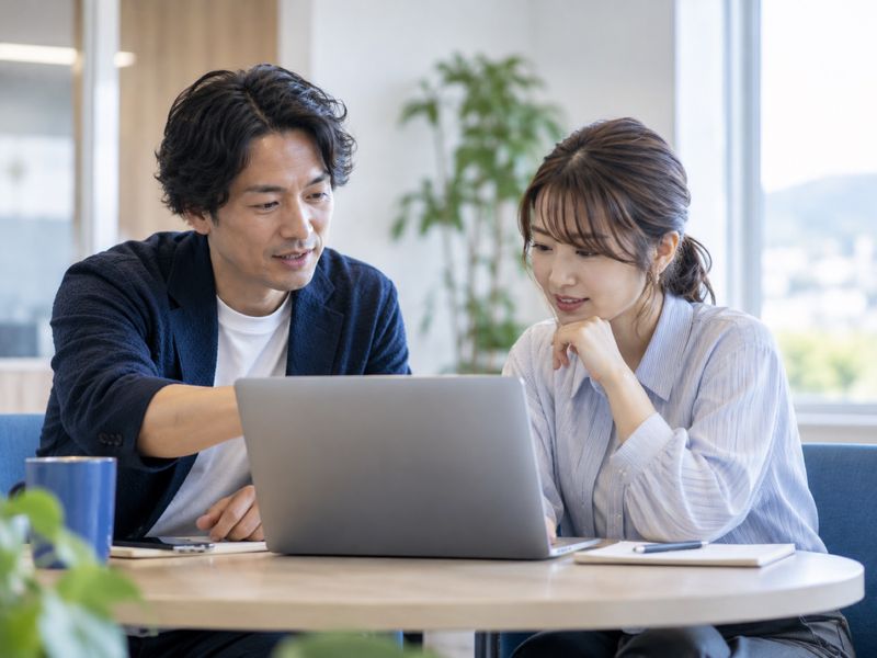 1台のノートPCを見ながら相談する担当者と社員